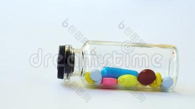 一个带有多色药丸和胶囊的小玻璃瓶滚出框架。